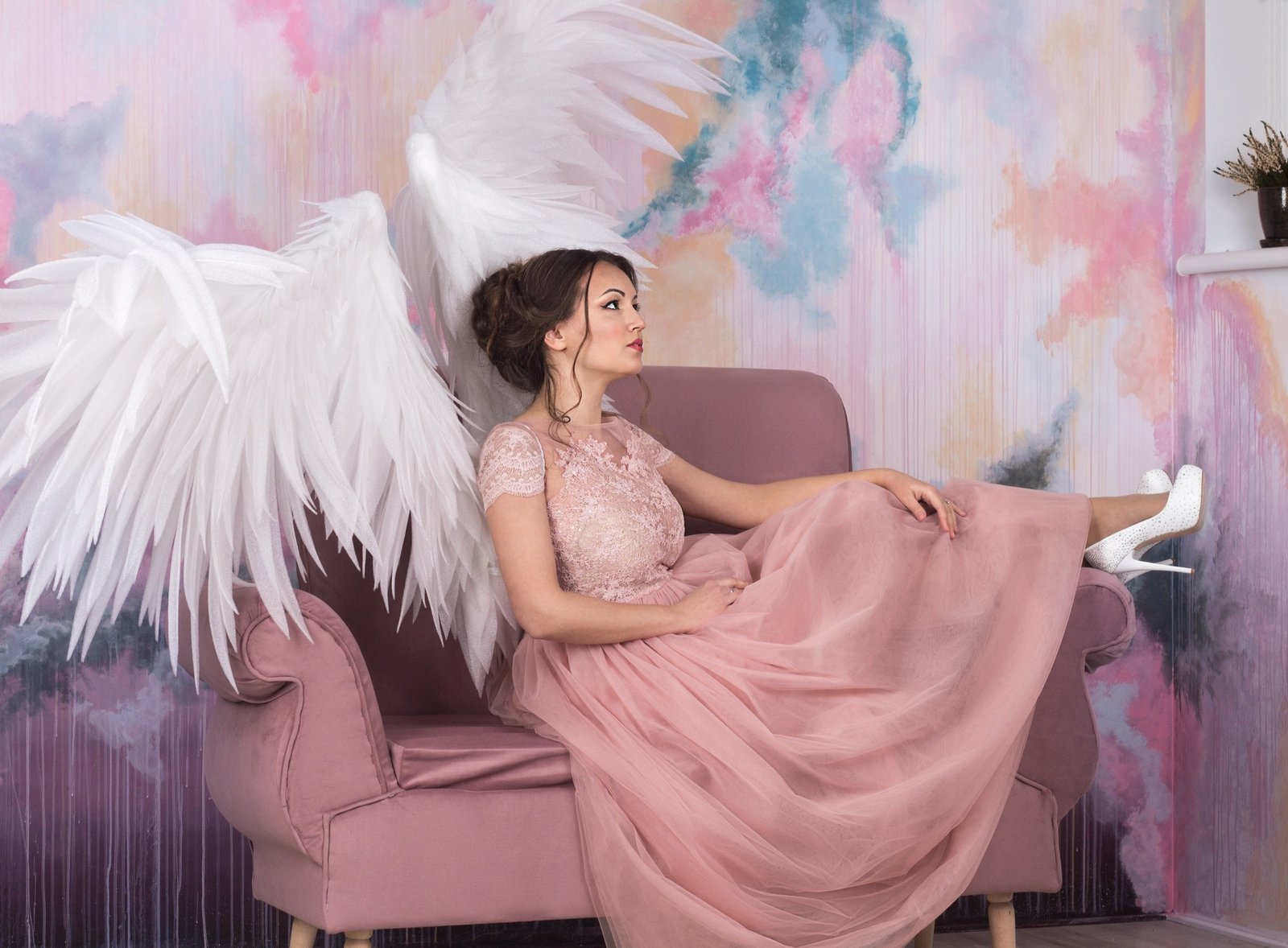 beautiful model with open angel wings sitting on the sofa