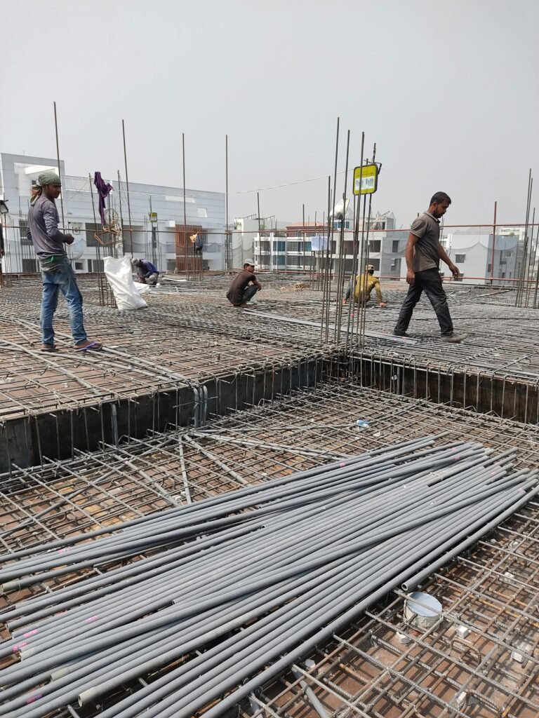 Workers engaged in construction on a building site, laying metal frameworks.